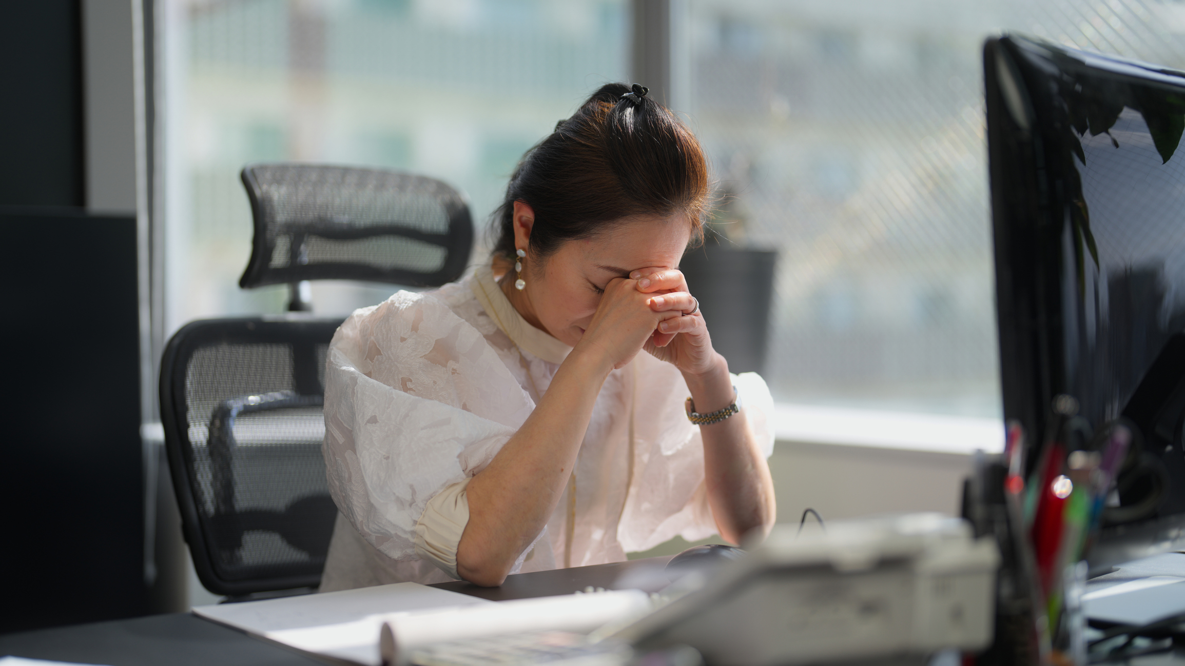 A widowed businesswoman is feeling stressed in an office.